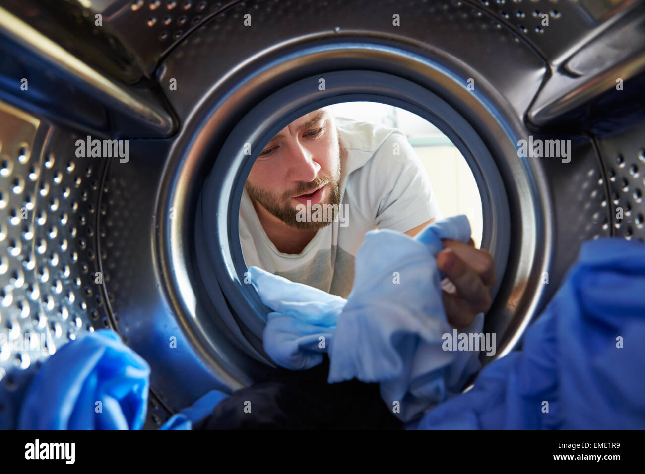 L'uomo accidentalmente la tintura di biancheria all'interno della macchina di lavaggio Foto Stock