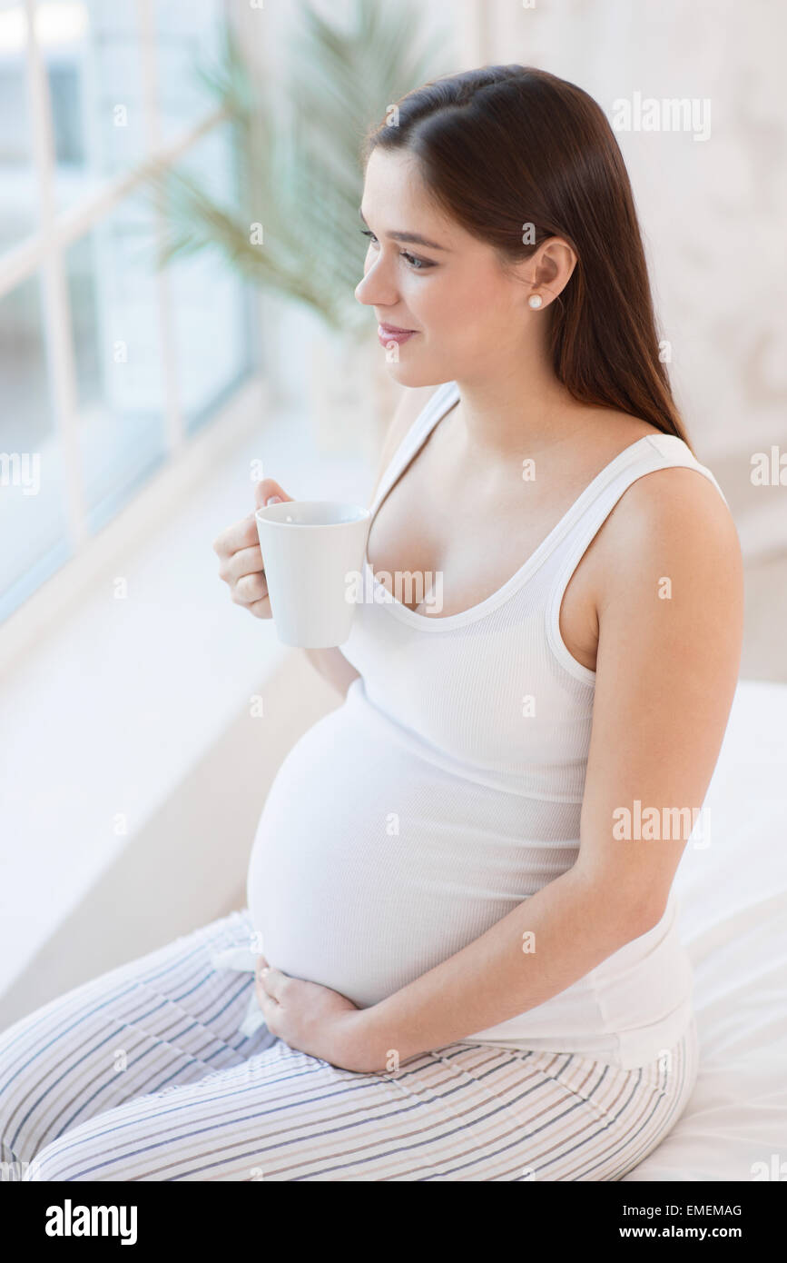 Giovane donna incinta bere il tè Foto Stock