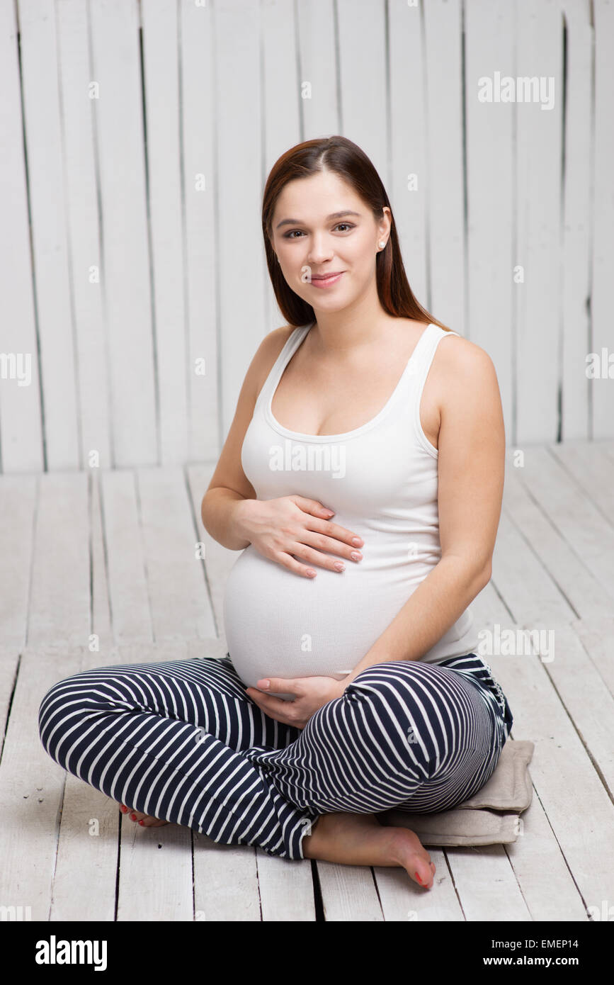 Donna incinta seduta nella posizione del loto Foto Stock