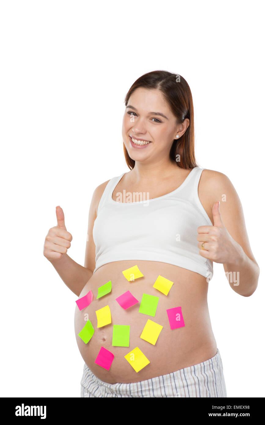 Sorridente donna incinta con carta colorata adesivi sul suo ventre Foto Stock