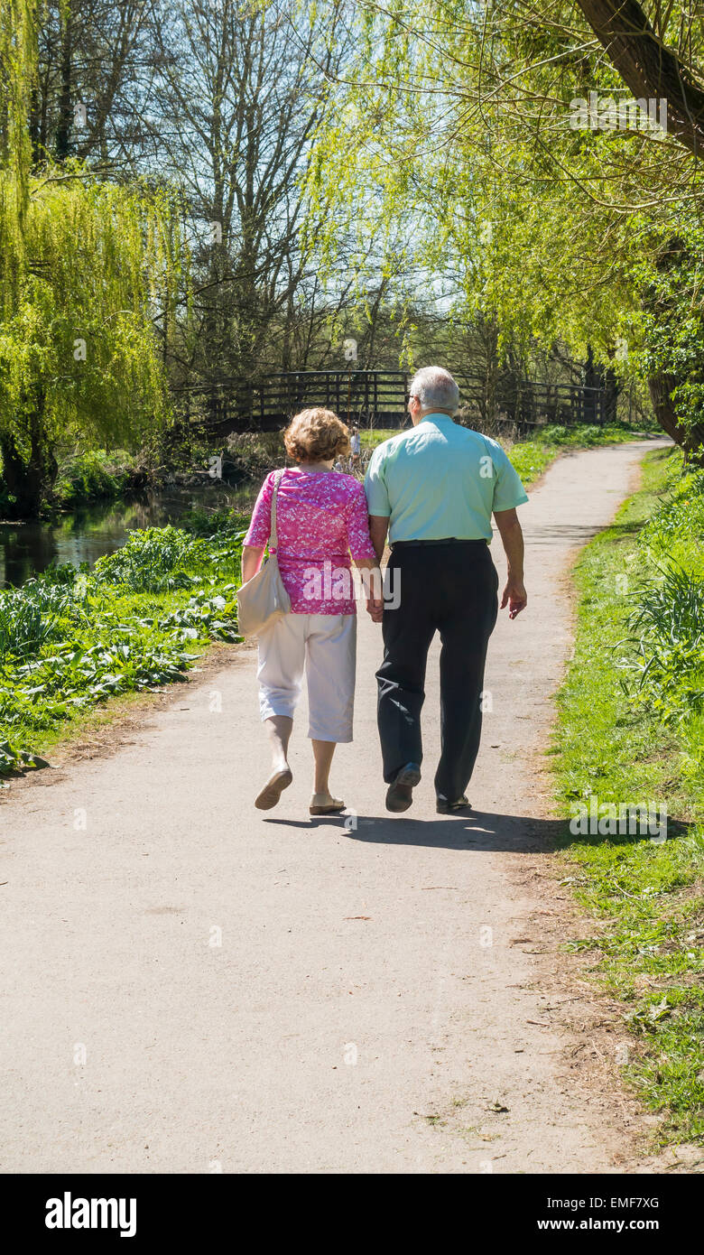 Coppia di anziani camminare tenendo le mani Riverside paese a piedi Foto Stock