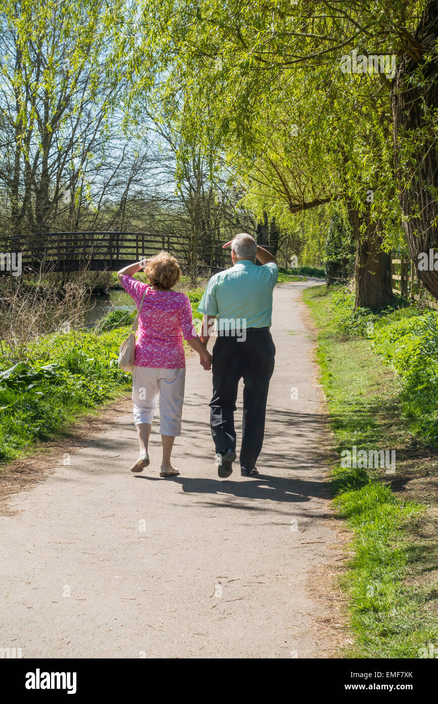 Coppia di anziani camminare tenendo le mani Riverside paese a piedi Foto Stock