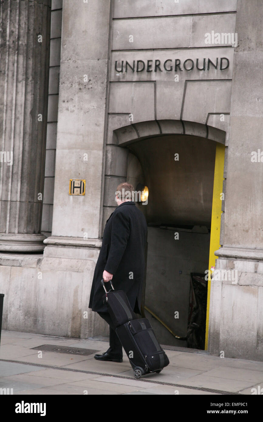 Imprenditore con carrello bagagli, al vecchio ingresso della metropolitana, il Royal Exchange di Londra, Inghilterra. Foto Stock