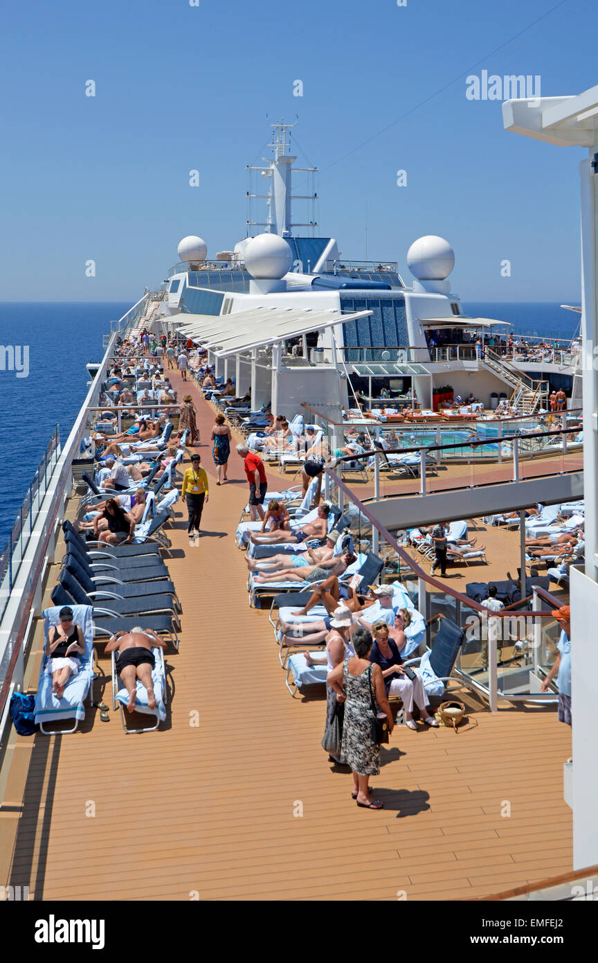 Vista sul solarium e sul ponte della piscina di una nave da crociera durante una calda giornata di sole in mare navigando nel Mar Mediterraneo Foto Stock