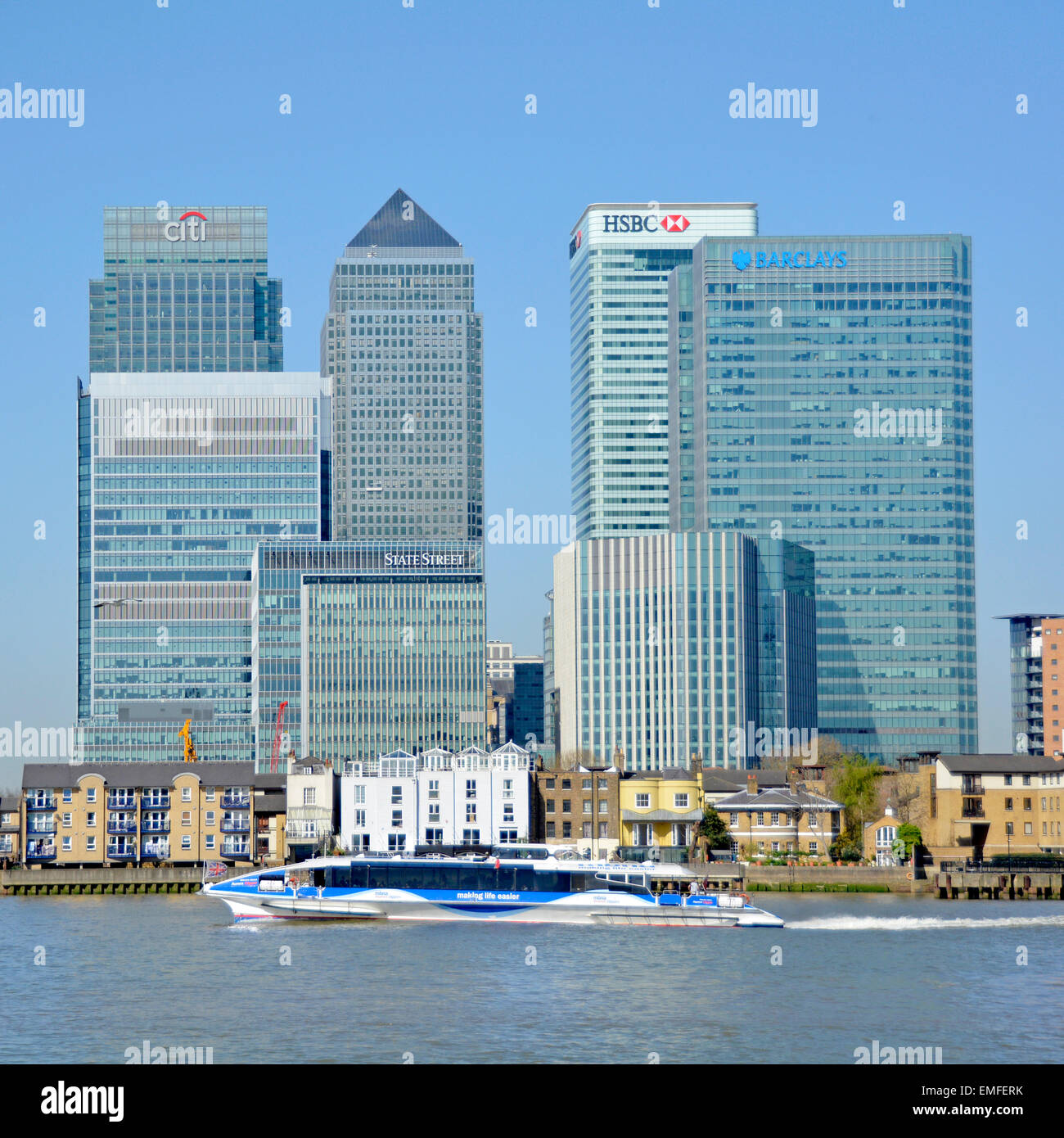 Docklands di Londra Canary Wharf skyline inclusi banche HQ edifici dal fiume con Thames clipper passante Foto Stock