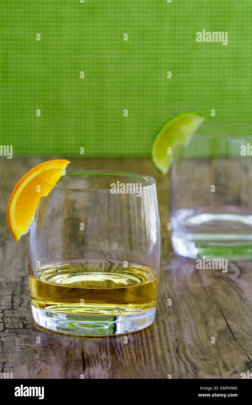 Alta qualità di tequila in un snifter con orange guarnire e argento tequila in sfondo sfocato Foto Stock