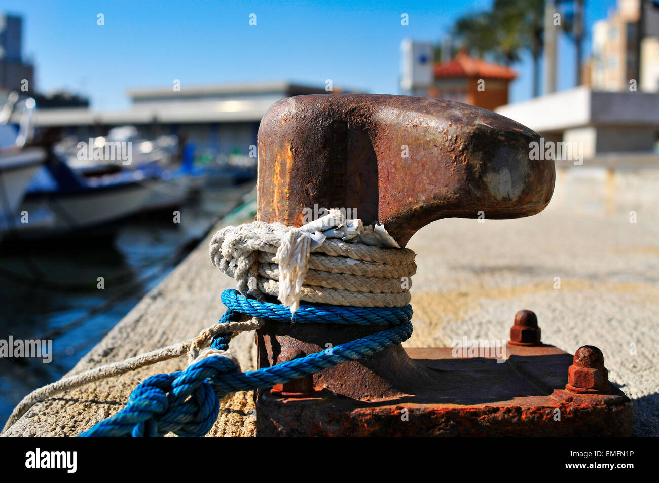 Primo piano di alcune funi legate a un arrugginito ormeggio nel porto Foto Stock