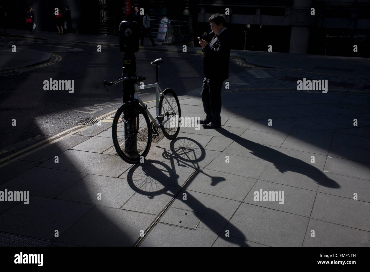 Il fumo dell'imprenditore e bloccato a noleggio nella luce del sole in angolo di un quartiere al di fuori di una grande città di Londra istituto finanziario in Lime Street. Foto Stock