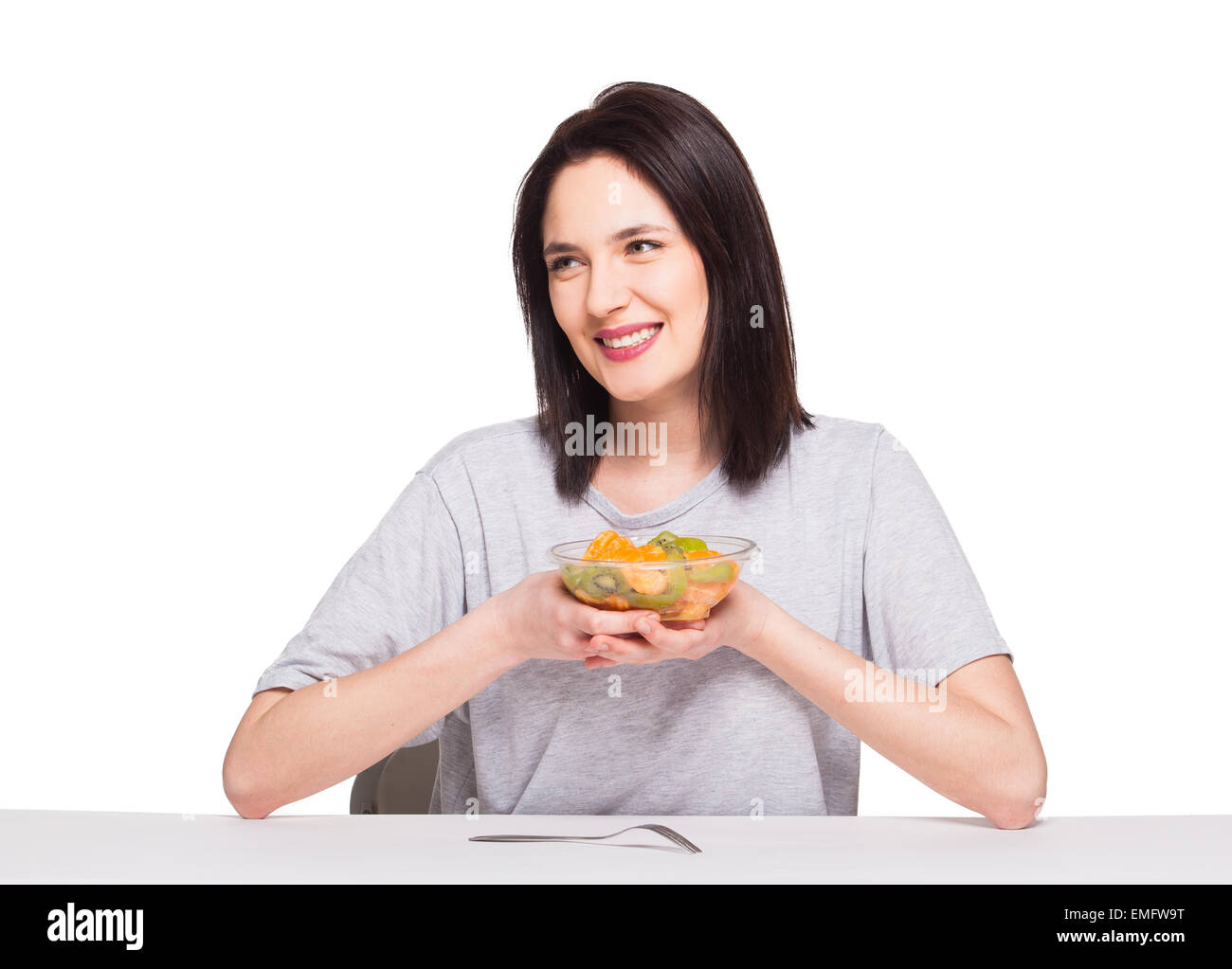 Bella donna sorridente e ansante un sani frutti pasto con arancia e kiwi, isolato su bianco Foto Stock