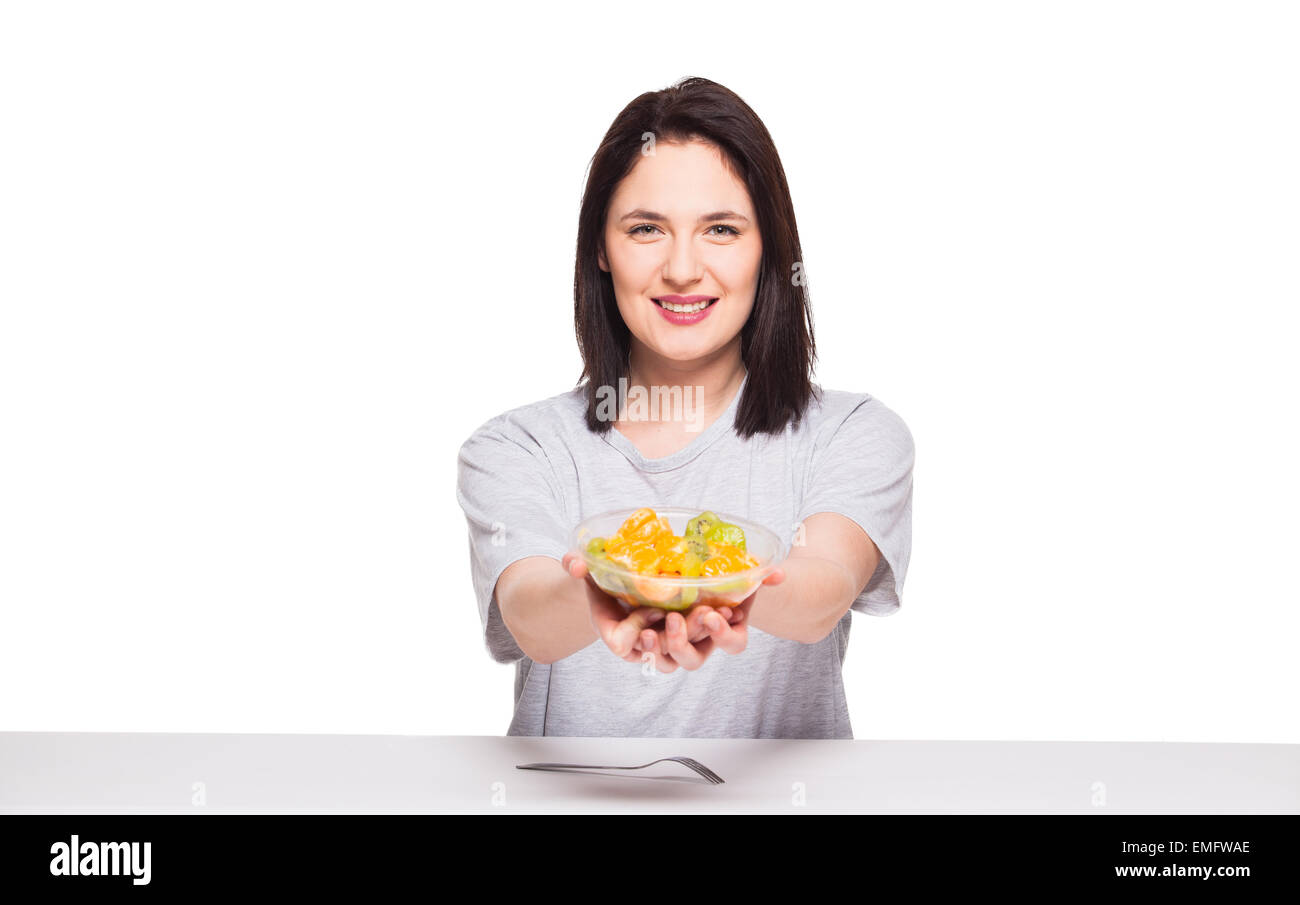 Bella donna sorridente e mostrando un sani frutti pasto con arancia e kiwi, isolato su bianco Foto Stock