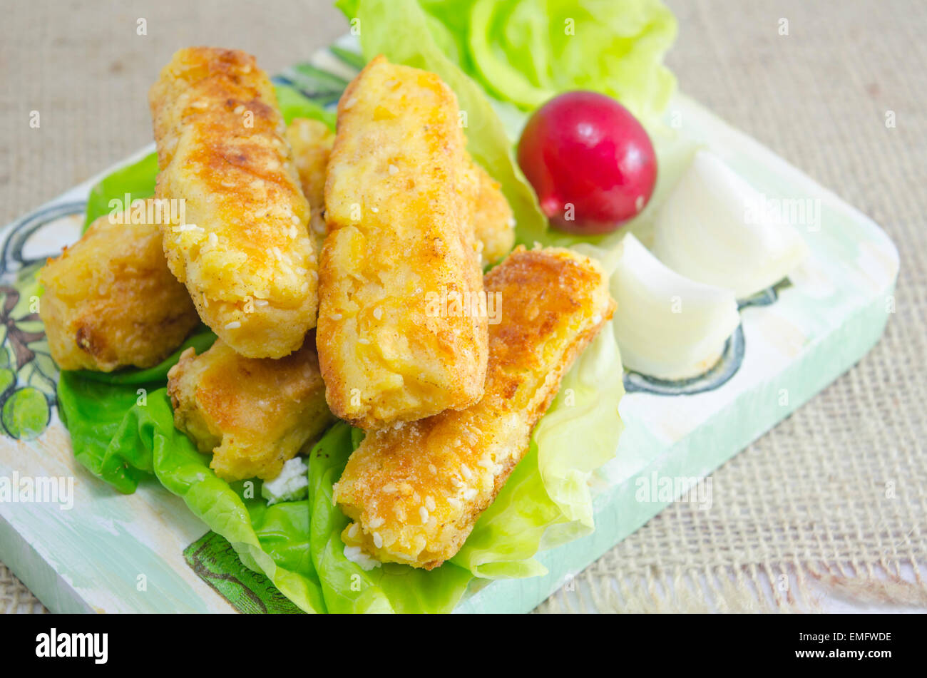 Home cotta torta di sesamo su un tagliere decorato con insalata verde Foto Stock