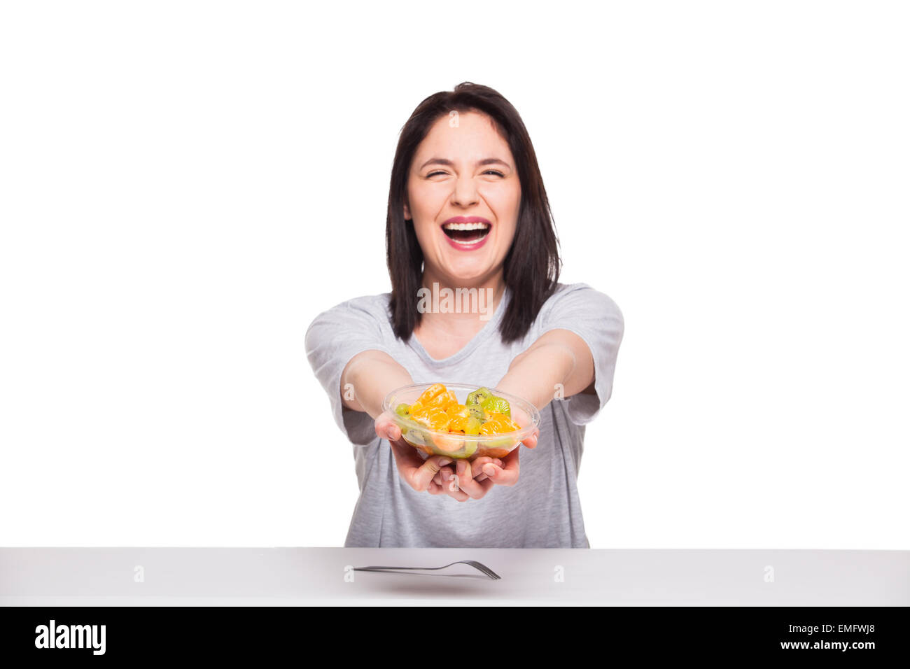 Bella donna sorridente e mostrando un sani frutti pasto con arancia e kiwi, isolato su bianco Foto Stock