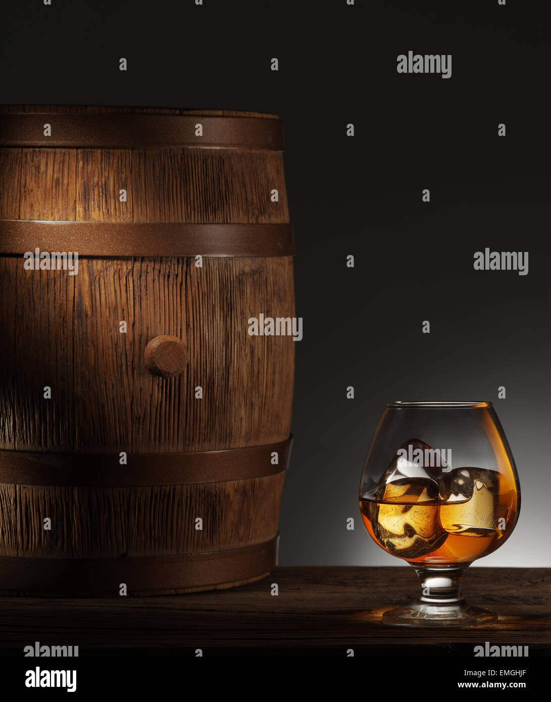 Bicchiere di whiskey maturata con cubetti di ghiaccio in esso e il vecchio Barile di legno. Foto Stock
