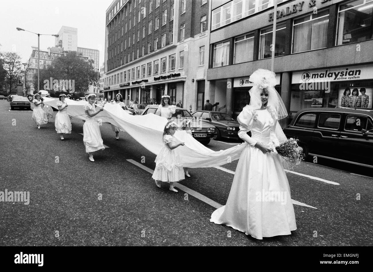 Modello Michelle Hardy e una squadra di bridesmaids mostrare il suo abito da sposa e un record di 50 piedi treno di seta adornata con rose a Londra il Bond Street. Il 3 novembre 1987. Foto Stock