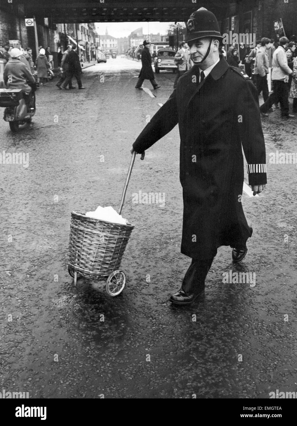 Un poliziotto ruote lontano un carrello degli acquisti contenente RSG opuscoli che è stata sequestrata come essi venivano distribuiti da Ken Browning a Chiswick, West London di manifestanti hanno sul Aldermaston marzo. Il 15 aprile 1963. Foto Stock