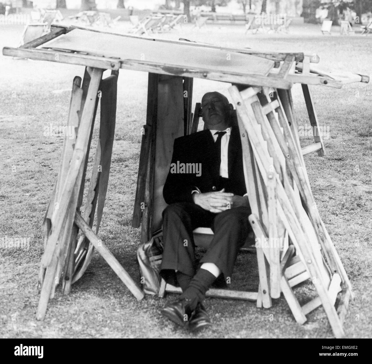 Uomo che utilizza qualsiasi materiali improvvisati egli può trovare compresi piegato sdraio a costruire un riparo dal sole implacabile come egli siede in St James Park durante un fine lunedì festivo. Il 4 giugno 1968. Foto Stock