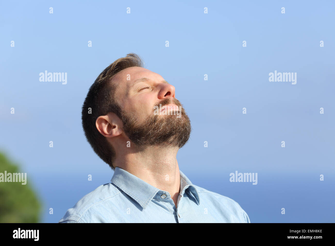 L'uomo respirazione profonda aria fresca all'aperto e con un cielo blu in background Foto Stock