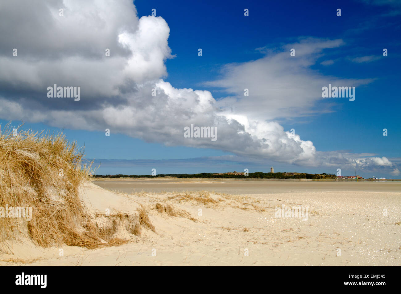 Lunga fila di nuvole sopra la vasta spiaggia dell'isola olandese di Terschelling, in prima linea una duna, sullo sfondo di un villaggio Foto Stock