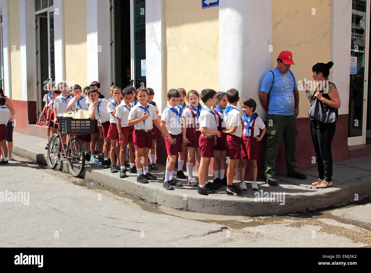 I giovani della scuola i bambini in uniformi di scuola attendere per cross street in Trinidad, Cuba Foto Stock