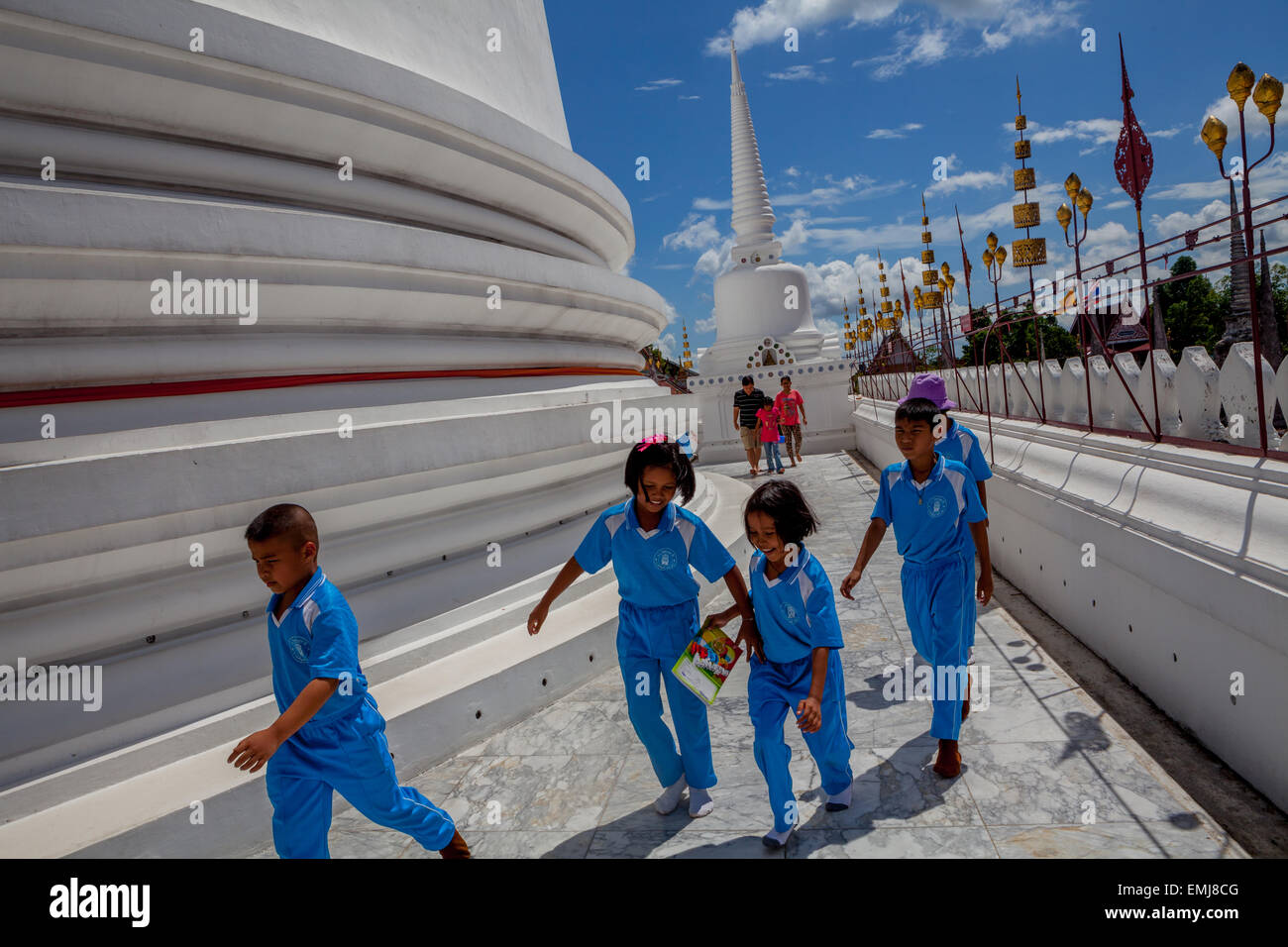 I bambini della scuola circondano principali stupa di Wat Phra Mahathat Woromaha Vihan, il più antico e il più importante chedi nel sud della Thailandia. Foto Stock