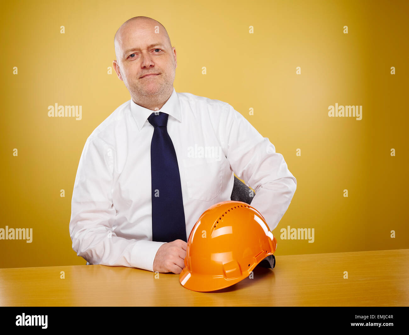 Ingegnere maschio in ufficio egli indossa una camicia bianca e cravatta, orange elmetto è sul tavolo Foto Stock