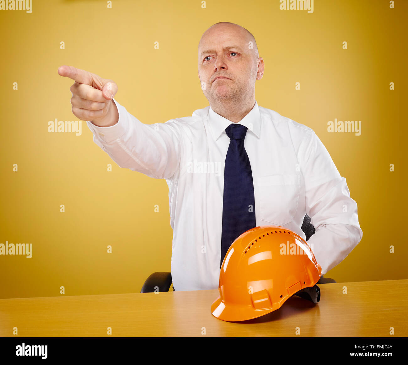 Ingegnere maschio in ufficio egli indossa una camicia bianca e cravatta, orange elmetto è sul tavolo Foto Stock