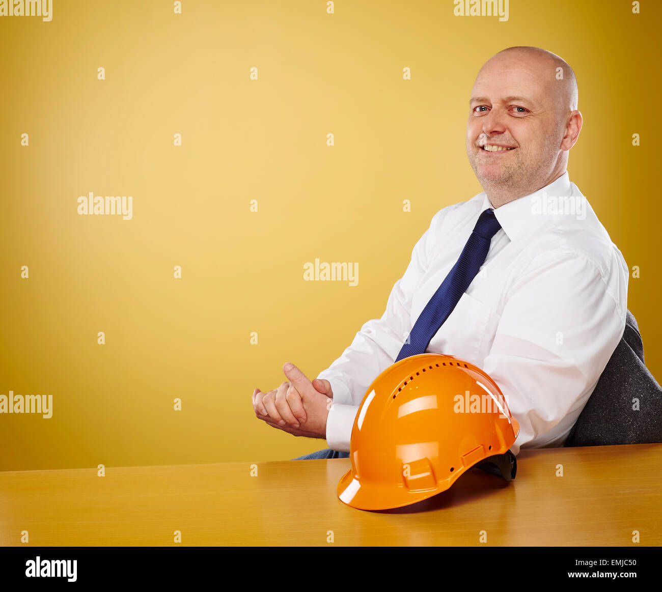 Ingegnere maschio in ufficio egli indossa una camicia bianca e cravatta, orange elmetto è sul tavolo Foto Stock