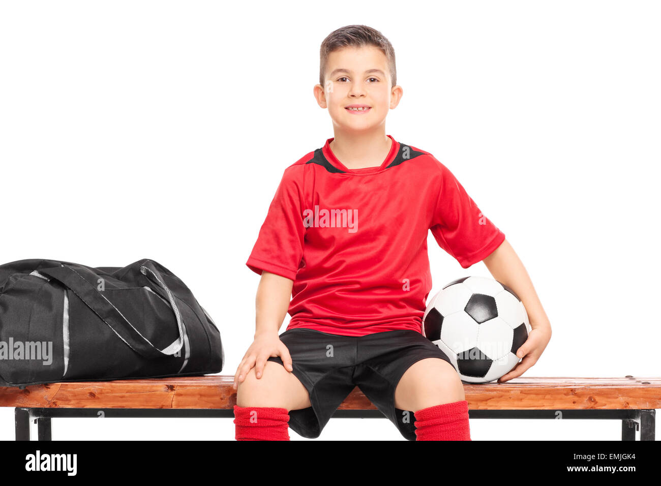 Junior Soccer giocatore seduto su una panchina e tenendo un calcio isolati contro uno sfondo bianco Foto Stock