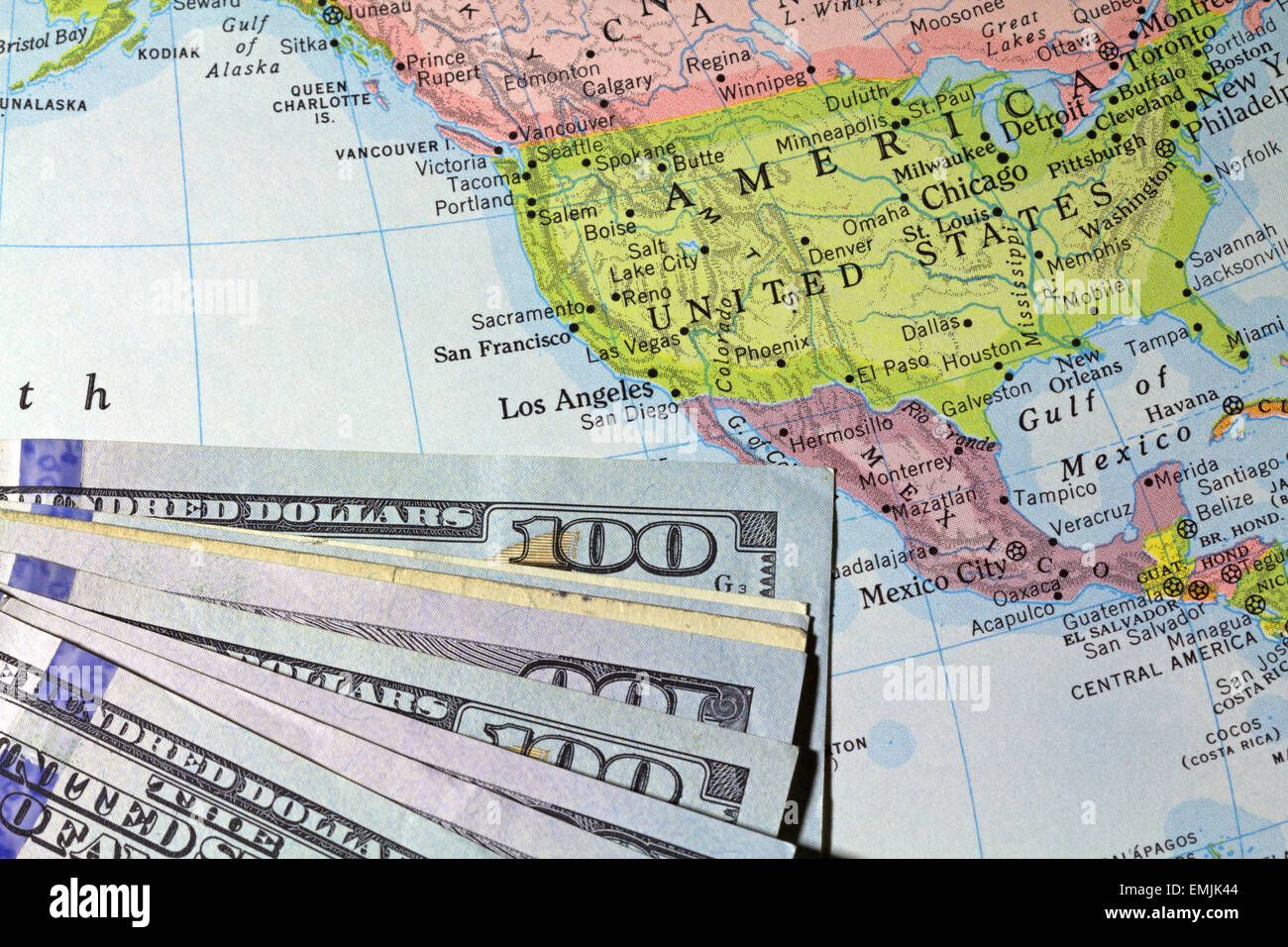 Una vista parziale di centinaia di fatture del dollaro sulla cima di un vecchio atlas mostra negli Stati Uniti e nei paesi circostanti. Foto Stock