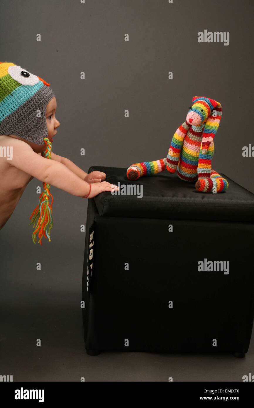 Baby tenendo premuto su di una scatola con un orsacchiotto di peluche sulla parte superiore. Foto Stock