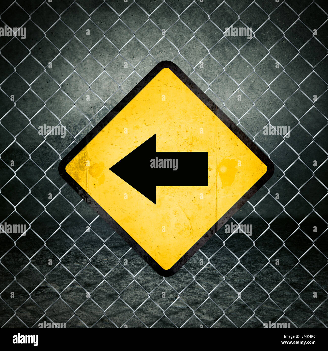A sinistra in direzione di grunge simbolo giallo di avvertimento sulla recinzione ad anelli di magazzini industriali Foto Stock