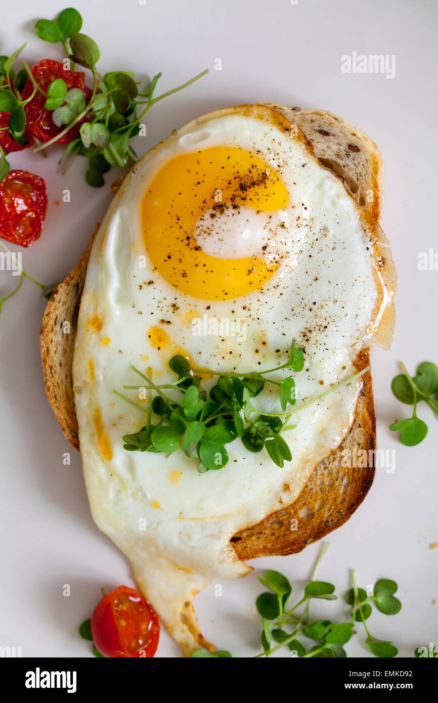 La prima colazione, le uova sul pane tostato con pomodorini e crescione Foto Stock