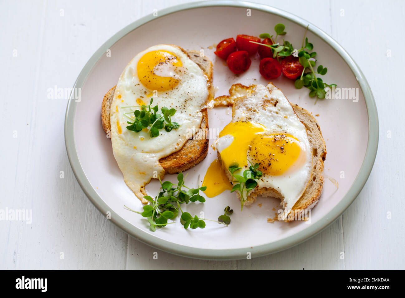 La prima colazione, le uova sul pane tostato con pomodorini e crescione Foto Stock
