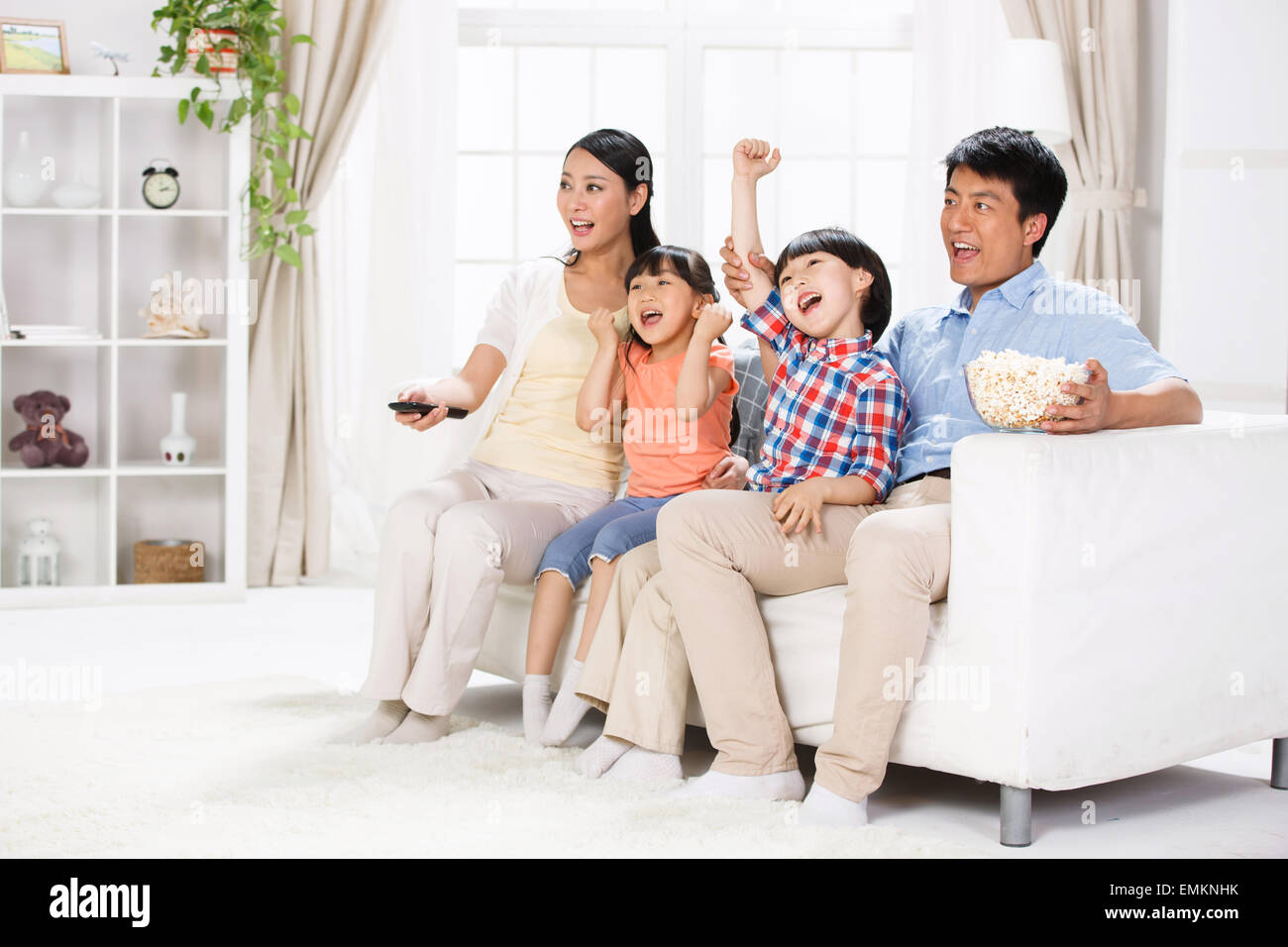 La gioia di una famiglia di quattro persone nel soggiorno per guardare la TV Foto Stock