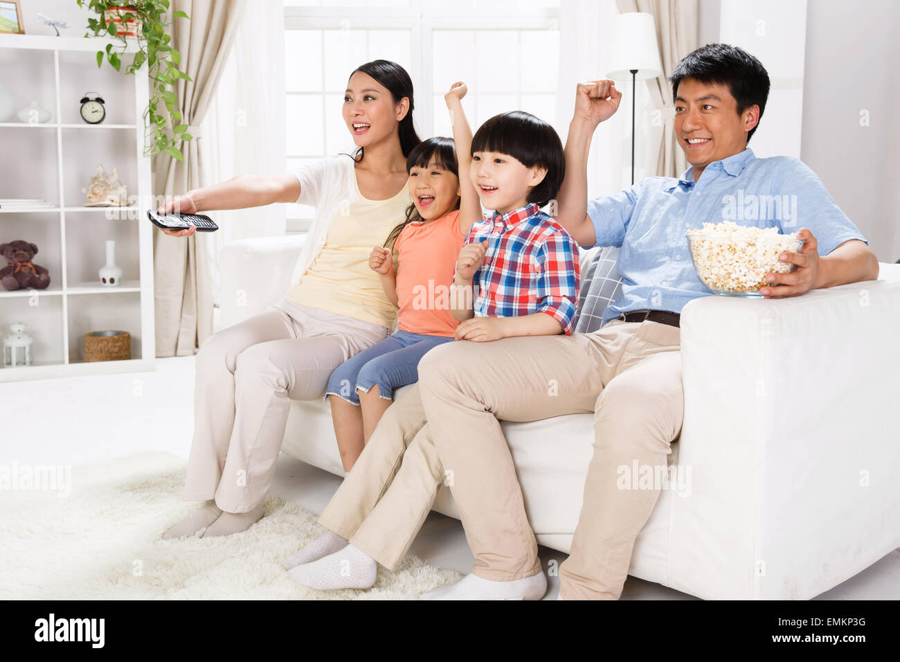 La gioia di una famiglia di quattro persone nel soggiorno per guardare la TV Foto Stock