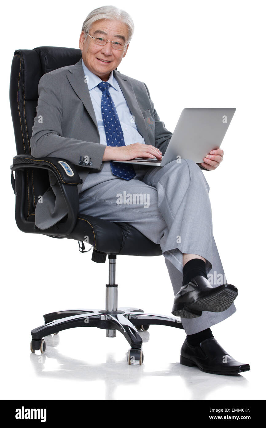 Un uomo anziano era seduto nella sedia boss per utilizzare un computer Foto Stock