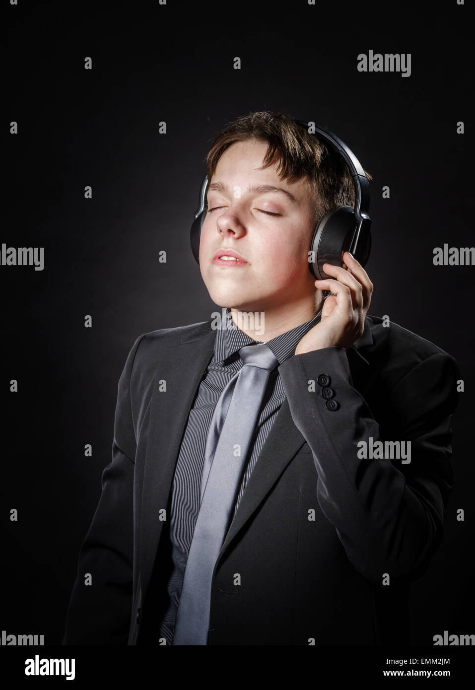 Ragazzo adolescente ascoltando la musica nelle cuffie isolato su sfondo nero Foto Stock