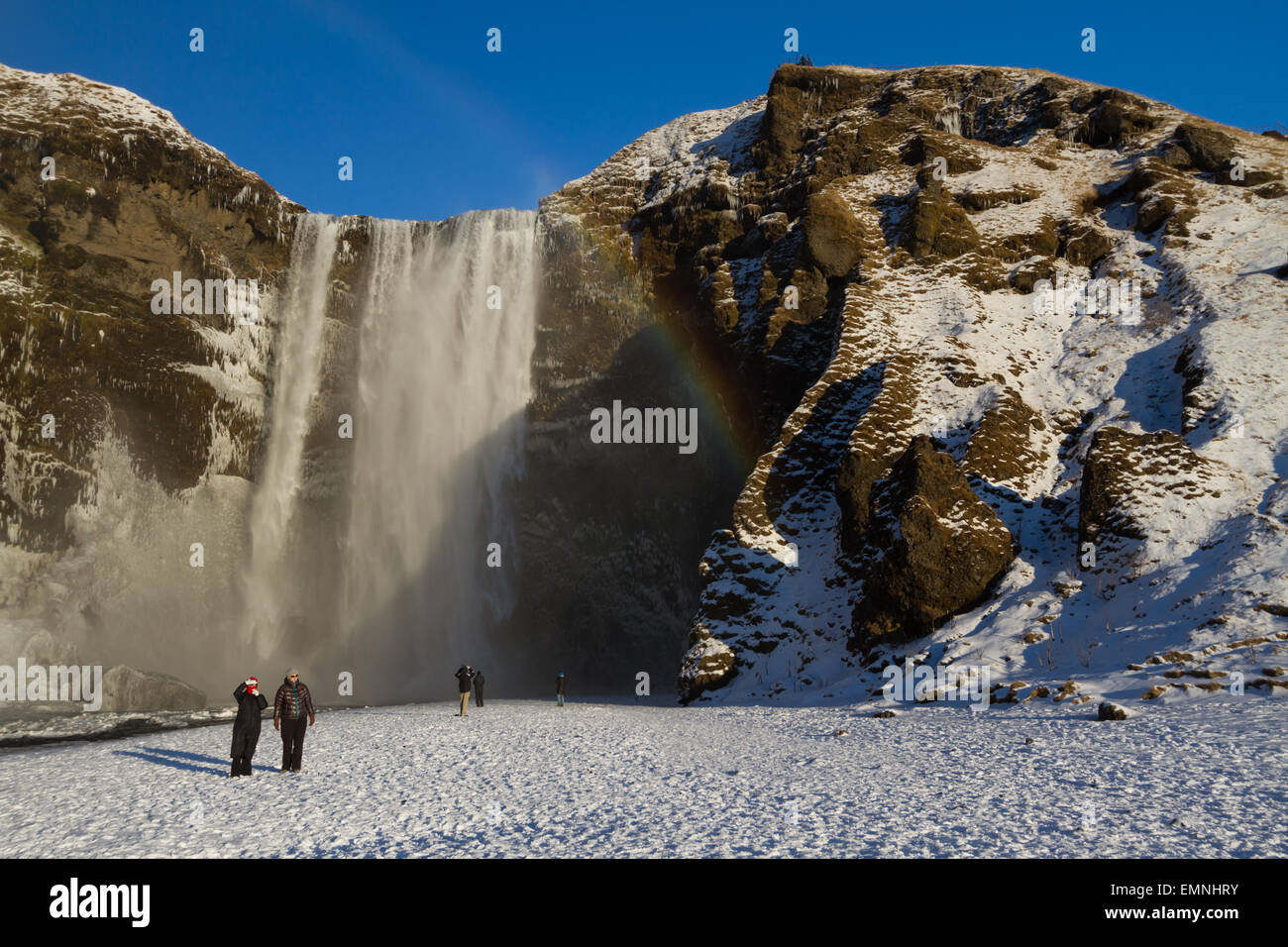 Ai turisti di ammirare la cascata Skogafoss in Islanda durante la breve giornata invernale Foto Stock