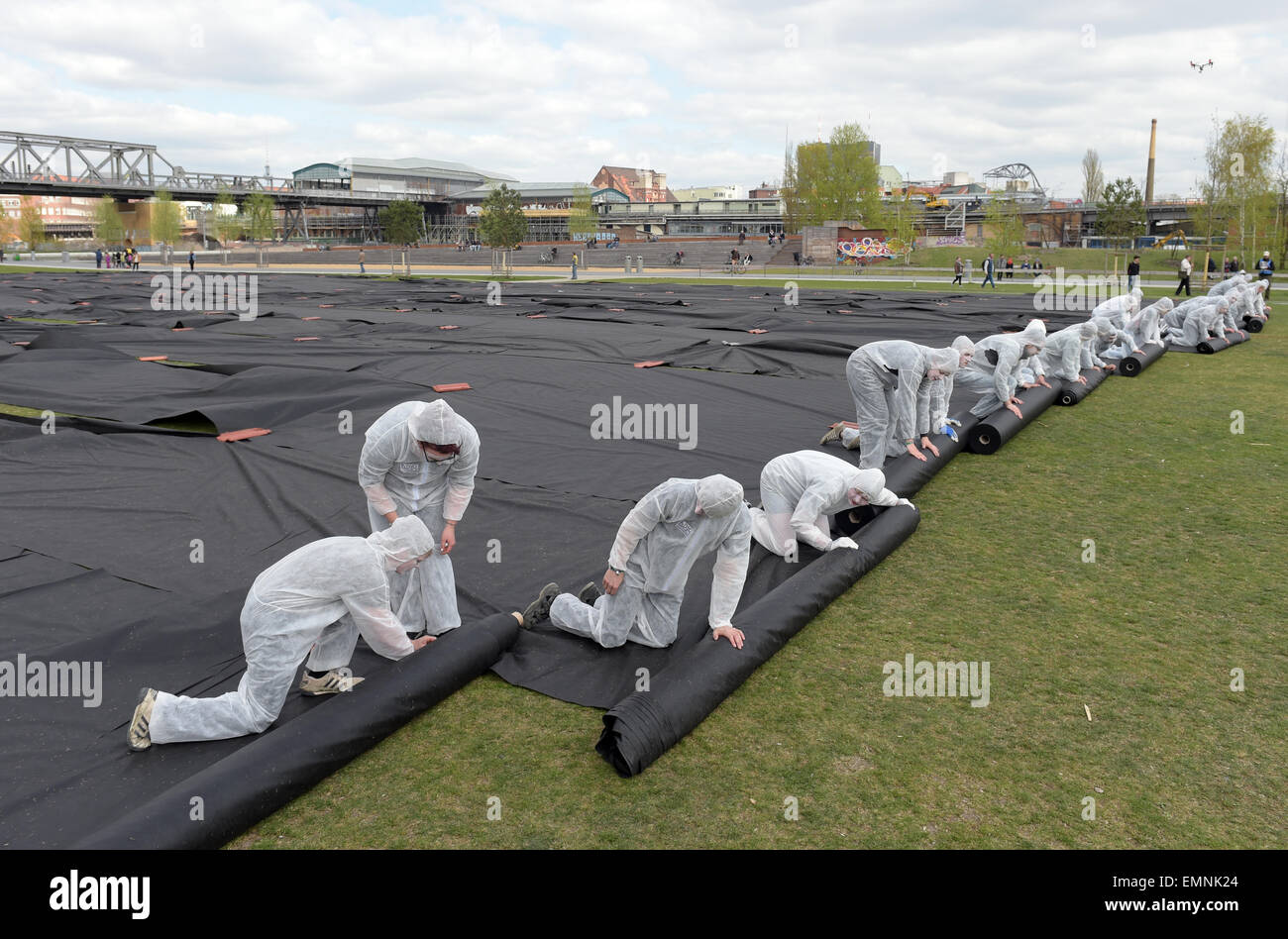 Artisti srotolare PVC nero su una superficie di un ettaro come parte dell'apertura dell'installazione 'un ettaro" di Berlino, Germania, 22 aprile 2015. Secondo l'organizzatore, l'installazione è destinato a sensibilizzare la coscienza del fatto che un ettaro di terreno in Germania è edificata ogni venti minuti. Gli iniziatori della manifestazione sono il Ministero tedesco per la Cooperazione Economica e lo sviluppo, l'Istituto per avanzati studi di sostenibilità (IAS) e la Deutsche Gesellschaft für Internationale Zusammenarbeit (GIZ, German Federal Enterprise per la cooperazione internazionale). Foto: RAINE Foto Stock