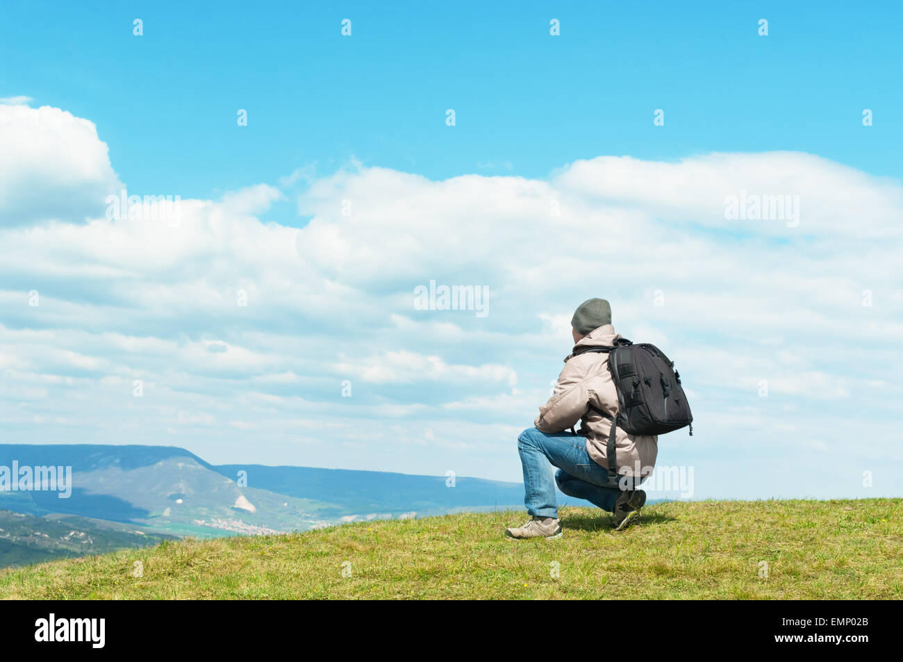 Uomo con uno zaino che guarda lontano sulla cima della collina. Foto Stock