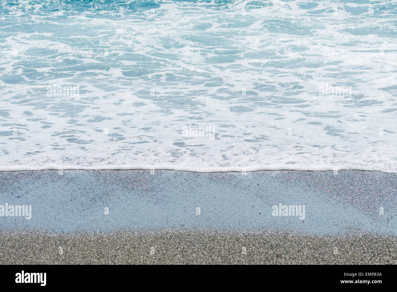 La marea su una spiaggia con sabbia bagnata. Foto Stock