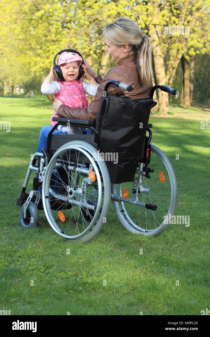 Una madre in una sedia a rotelle con il bambino sul suo giro Foto Stock
