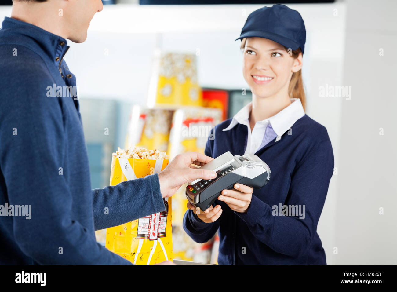 Lavoratore che accetta il pagamento tramite la tecnologia NFC dall uomo in cine Foto Stock