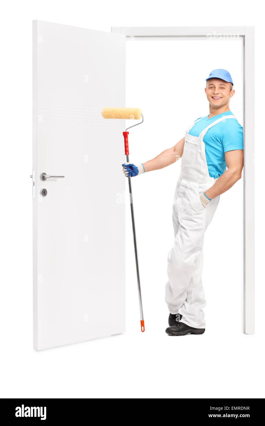 A piena lunghezza Ritratto di una giovane pittore tenendo un rullo di vernice e poggiante sul telaio di una porta aperta Foto Stock