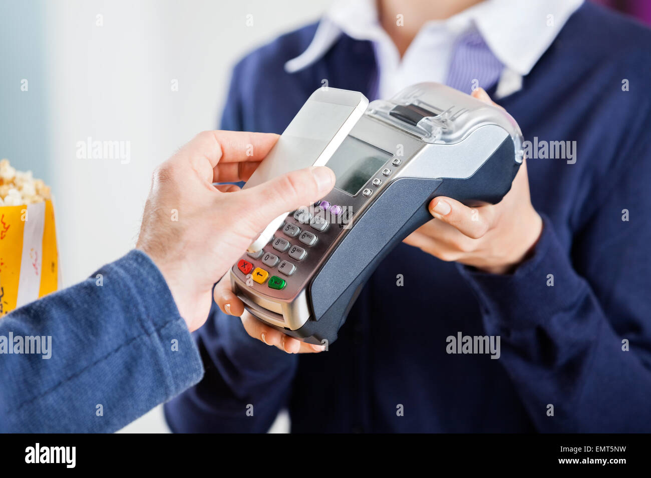 Uomo che utilizza la tecnologia NFC per pagare bill al cinema Foto Stock