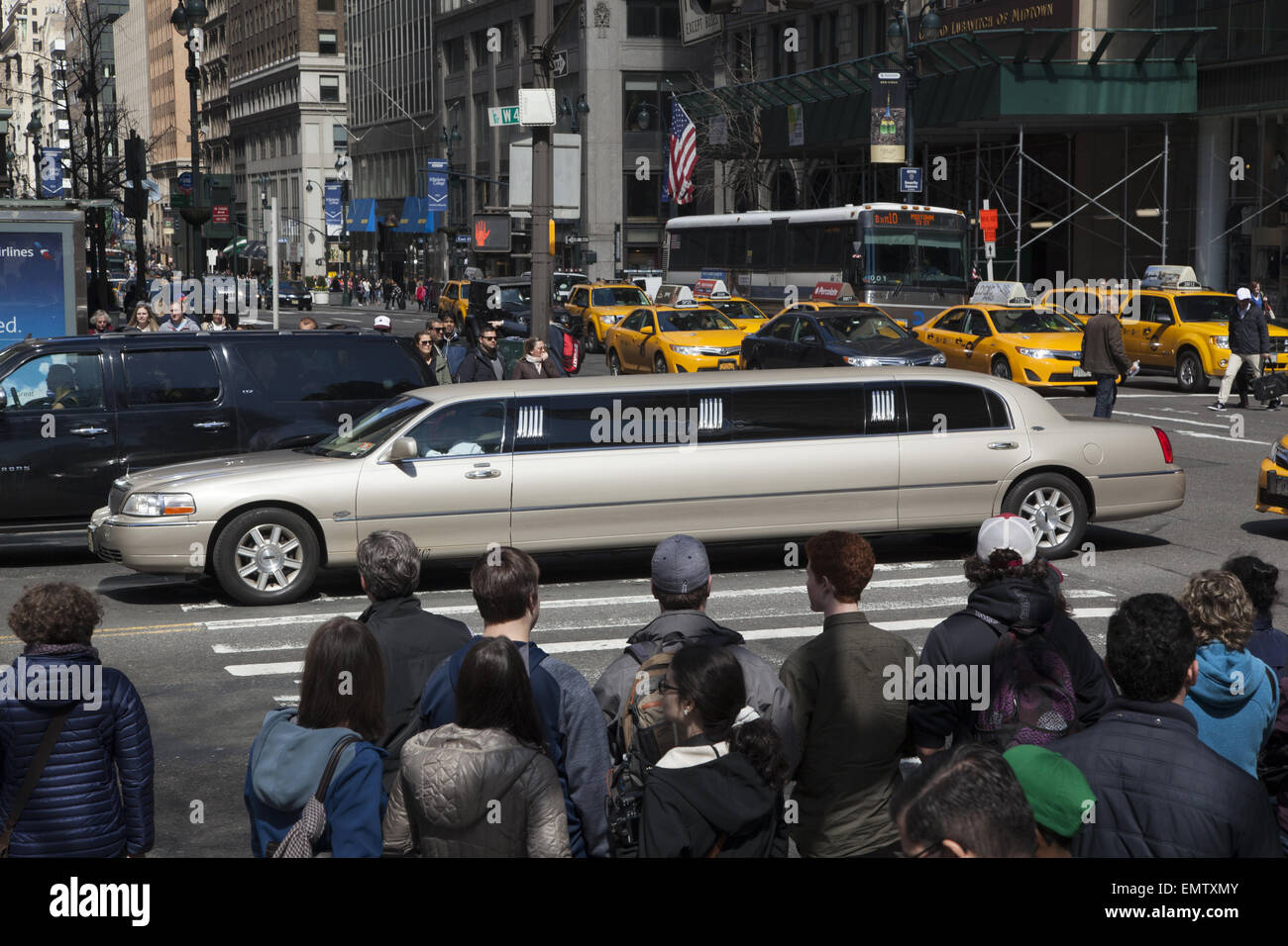 Una limousine stretch attraversa 5th Ave sulla 42nd St., un angolo che è sempre affollato di pedestreians. Foto Stock