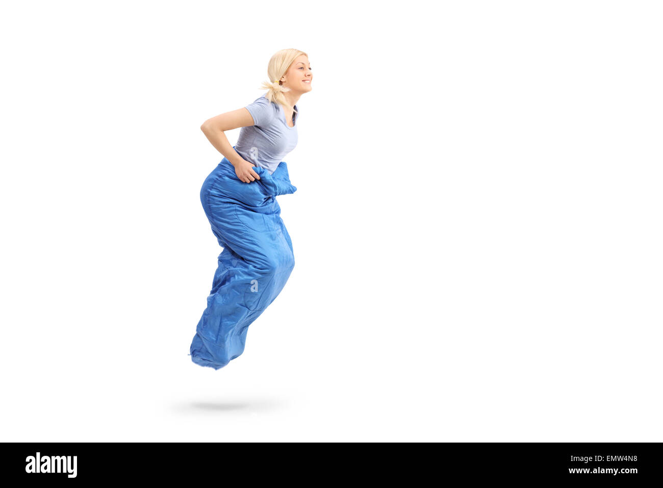 Colpo di profilo di una giovane donna bionda sacco di saltare in un sacco blu isolato su sfondo bianco Foto Stock