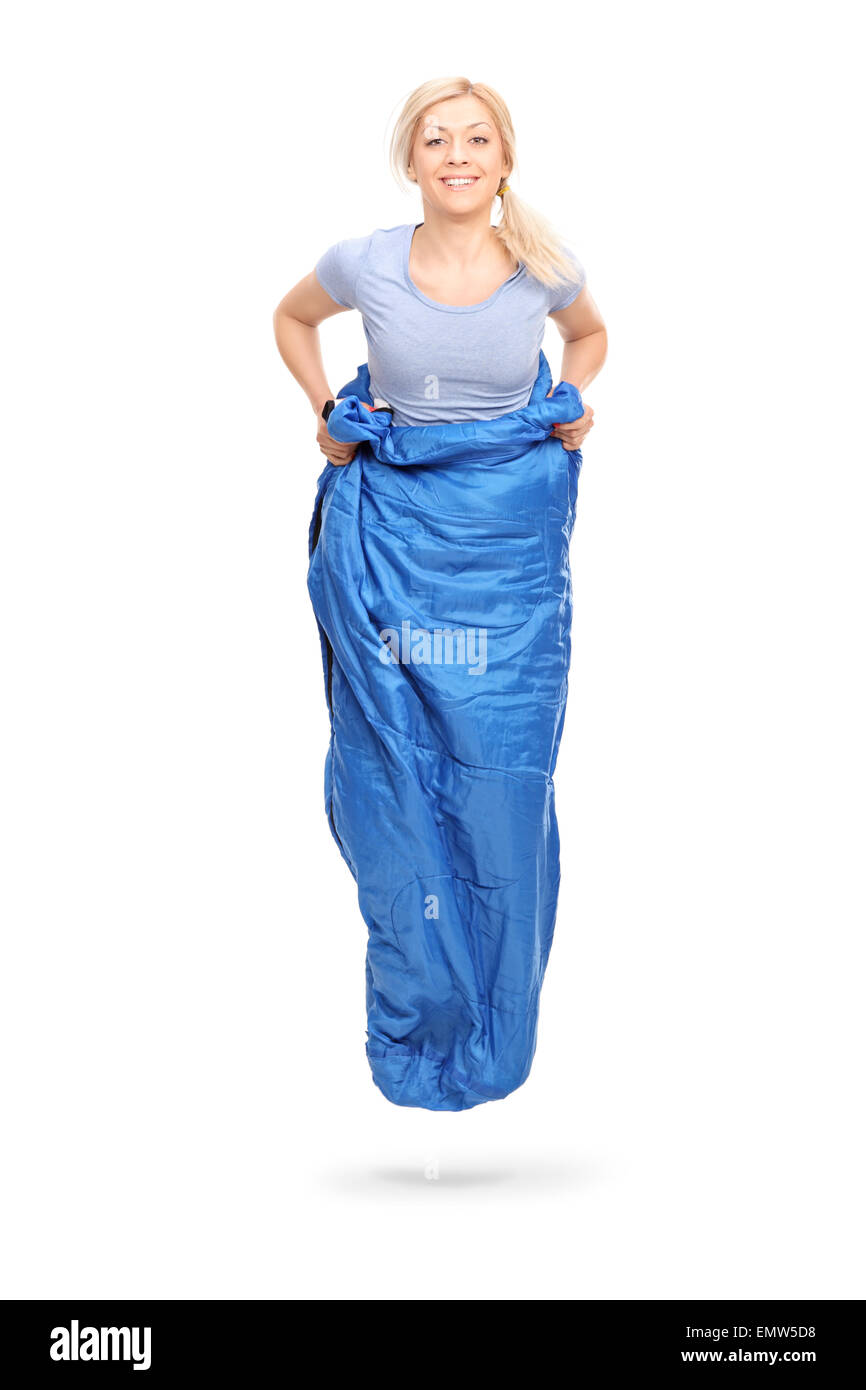 Colpo verticale di una giovane donna bionda jumping in un sacco blu isolato su sfondo bianco Foto Stock