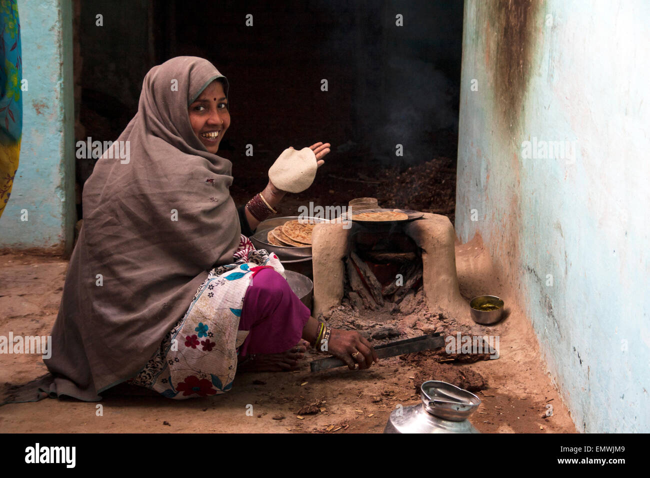 Local signora indiana cuoce pane naan sulla stufa in Agra, India Foto Stock