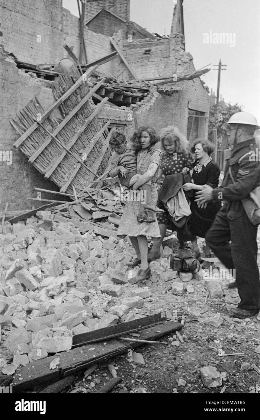 Shock sulle facce di una famiglia così come essi sono assistiti da un ARP operaio dopo un raid. 1940 Foto Stock
